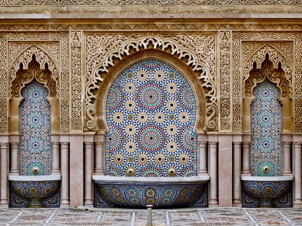Islamic geometric tilework and carved arches in a Moroccan courtyard